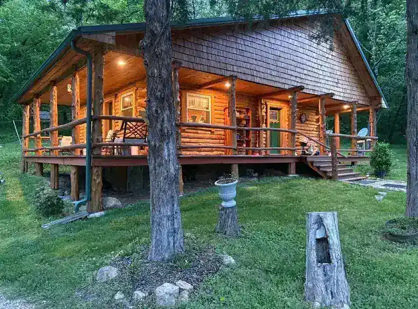 Restored luxury log cabin exterior at dusk with warm interior lighting